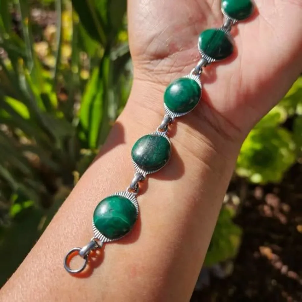 Malachite bracelet features natural green gemstones set in a silver colored link